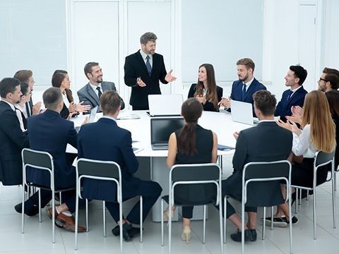 Business meeting with diverse professionals around a conference table, leader presenting, teamwork concept.