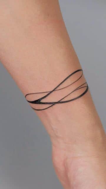 Minimalist loop tattoo around forearm, black ink design on light skin.