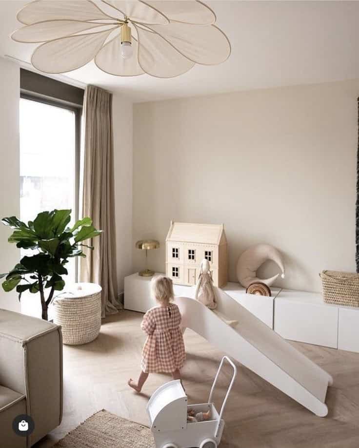 Child in modern playroom with slide, dollhouse, and plant. Neutral decor with natural light.