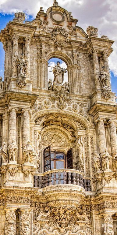 Ornate Baroque facade with detailed sculptures and intricate carvings under a blue sky.