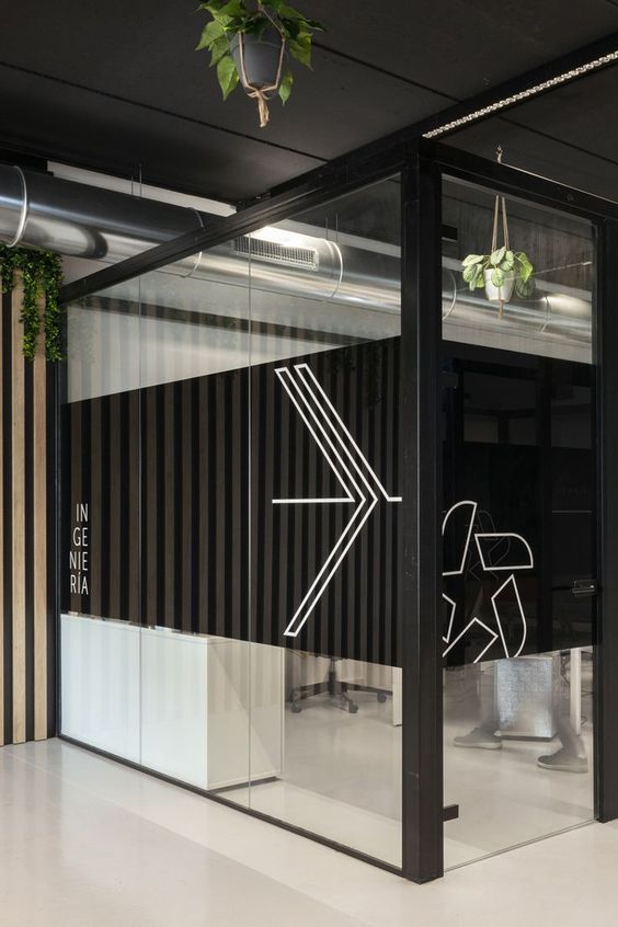 Modern office interior with glass walls, geometric design, and plants. Black and white minimalist style decor.