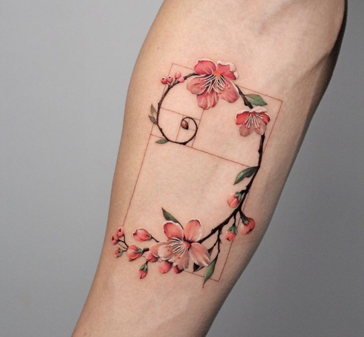 Tattoo of pink cherry blossoms intertwined with a geometric spiral on an arm.