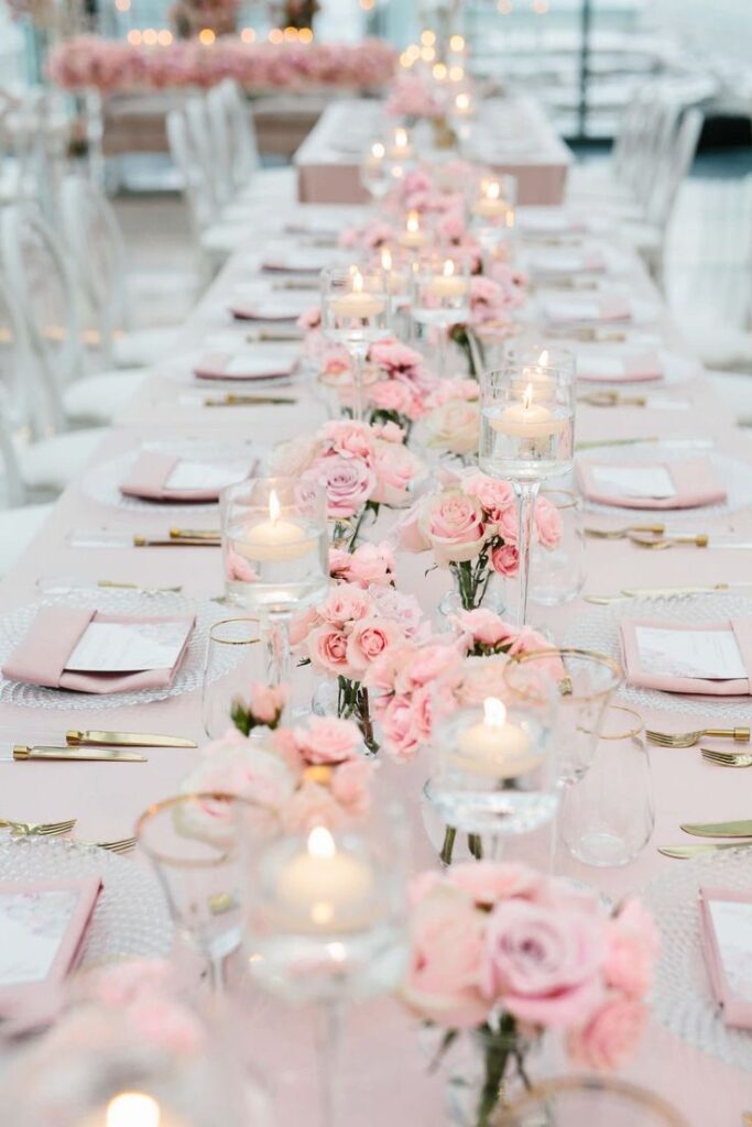 Elegant wedding table decor with pink roses and candles, creating a romantic and sophisticated ambiance.