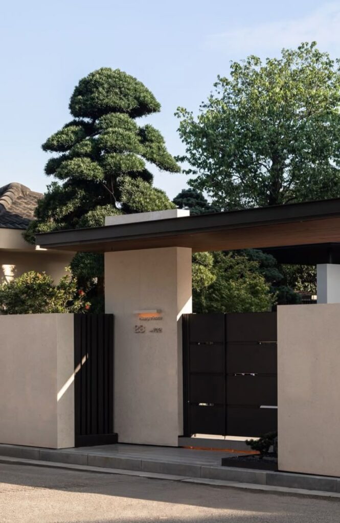 _ 48 Modern house entrance with minimalist design, featuring sleek gate and sculpted trees under a clear blue sky. | Sky Rye Design Modern house entrance with minimalist design, featuring sleek gate and sculpted trees under a clear blue sky.