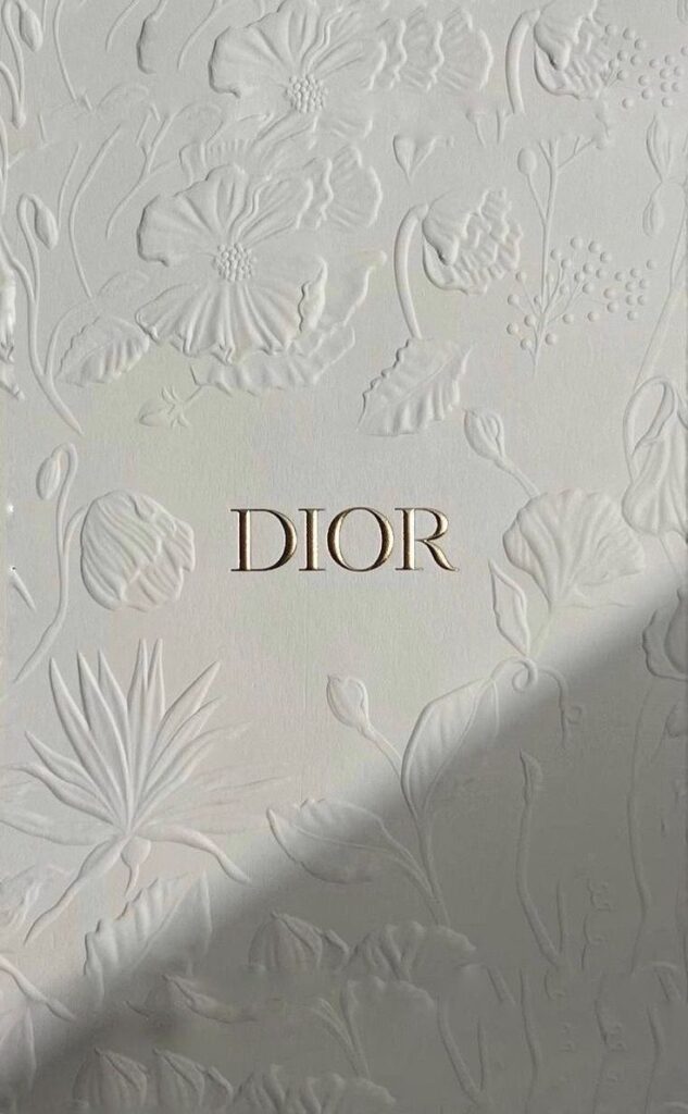 Elegant Dior logo on embossed floral background, showcasing luxury design and intricate patterns.