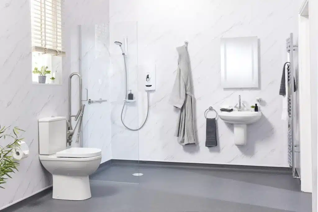 Modern accessible bathroom with toilet, shower, and sink. Features grab bars, gray flooring, and white marble walls.