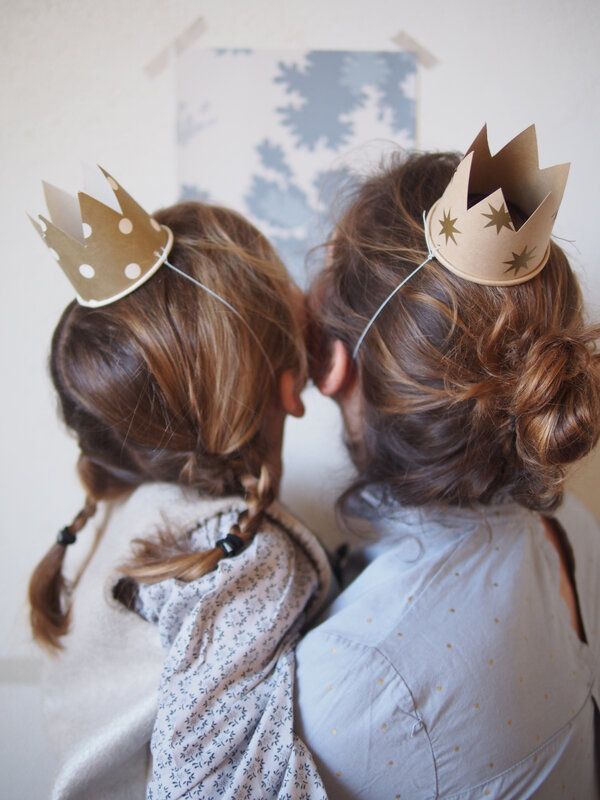 Two people wearing paper crowns and facing away, showcasing DIY family fun and creativity.