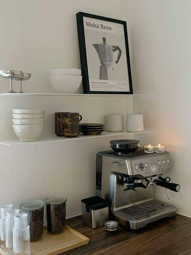 Home coffee station with espresso machine, shelves with cups, jars of coffee beans, and decorative Moka pot poster.