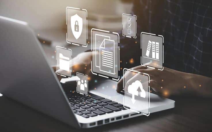 Person typing on laptop with holographic security and cloud storage icons floating above the keyboard.