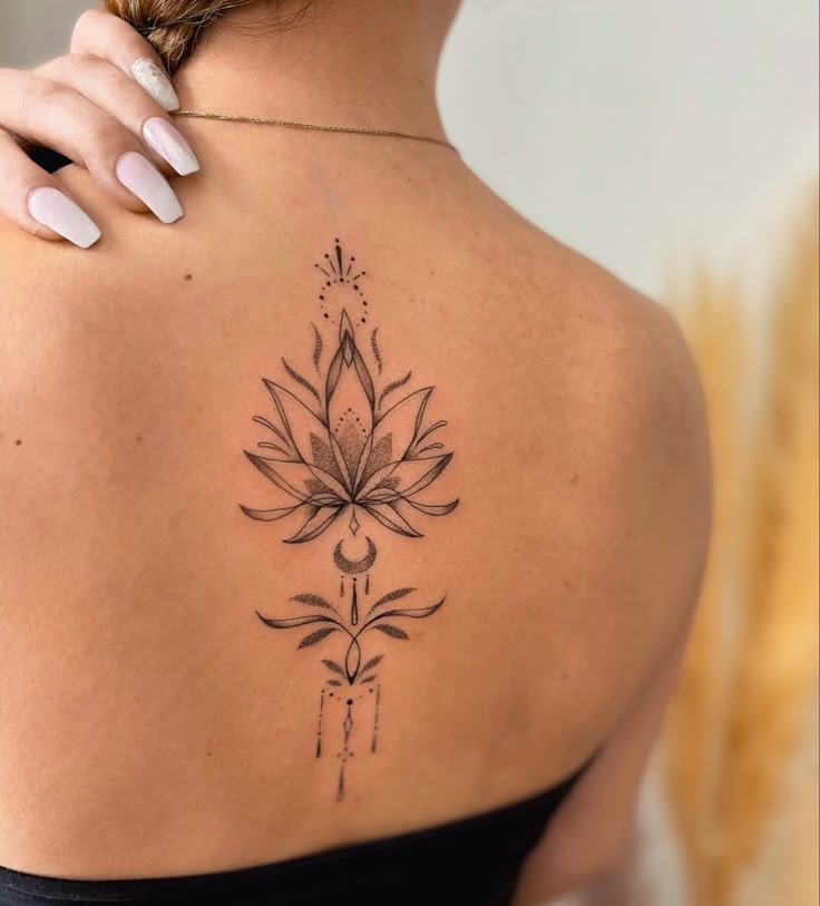 Ornate lotus flower tattoo on woman's back, featuring intricate details and delicate shading.