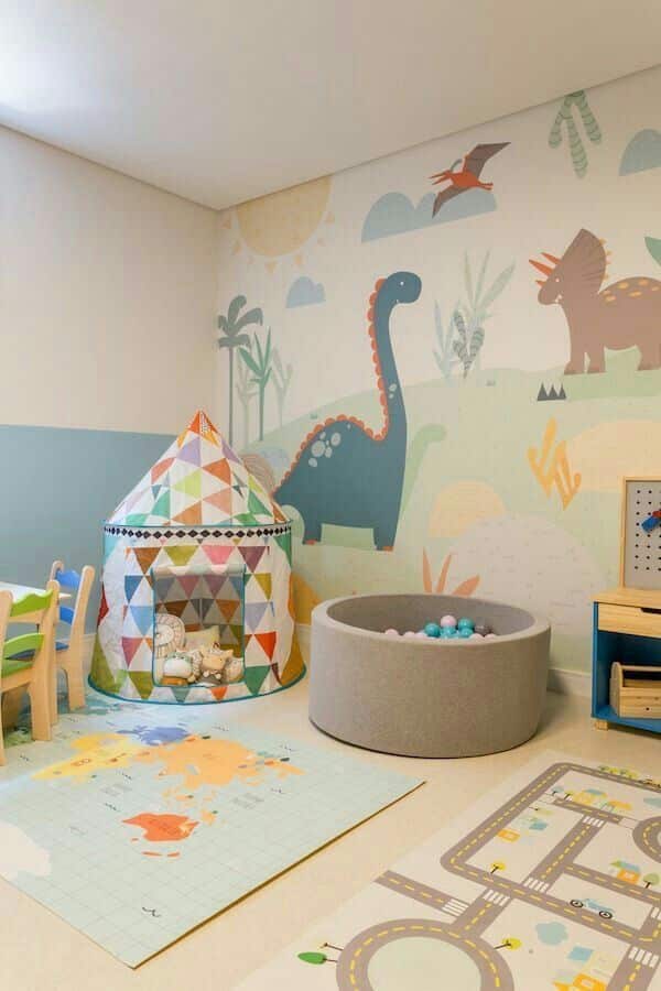 Playful children's room with dinosaur mural, colorful play tent, and ball pit for fun and imaginative play.