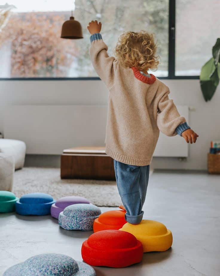 Child balancing on colorful stepping stones in cozy living room, enhancing motor skills and indoor playtime fun.