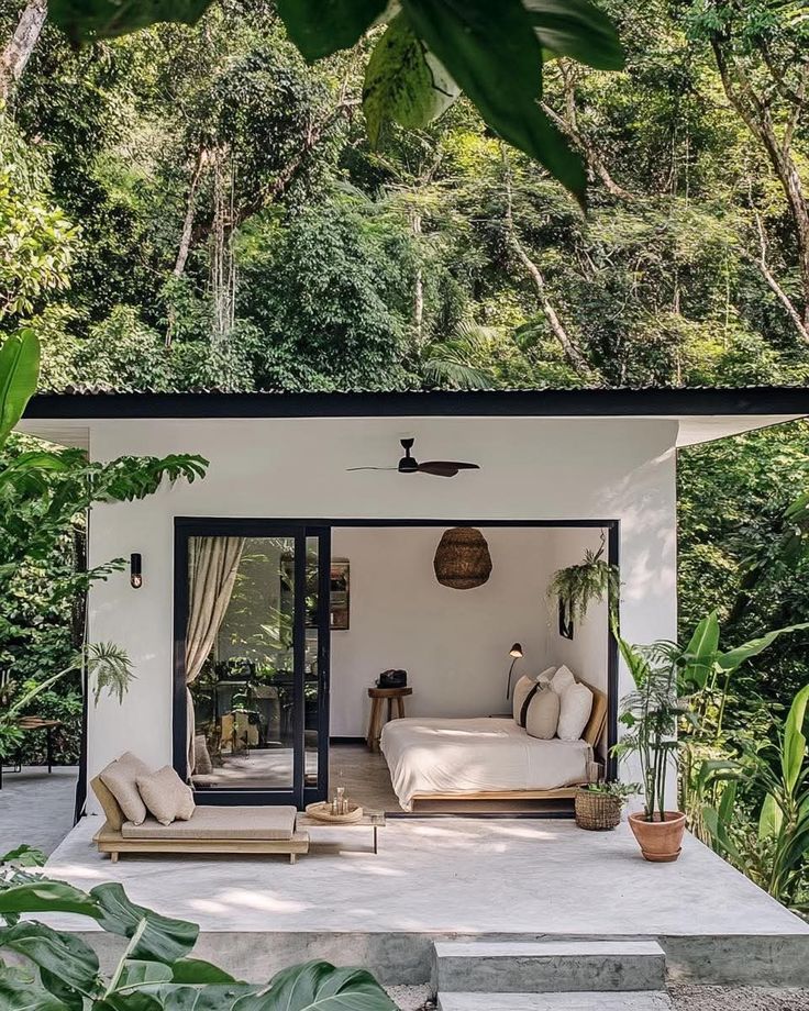 _ 6 Modern minimalist forest cabin with open glass doors, cozy bedding, and lush greenery surrounding the serene retreat. | Sky Rye Design Modern minimalist forest cabin with open glass doors, cozy bedding, and lush greenery surrounding the serene retreat.