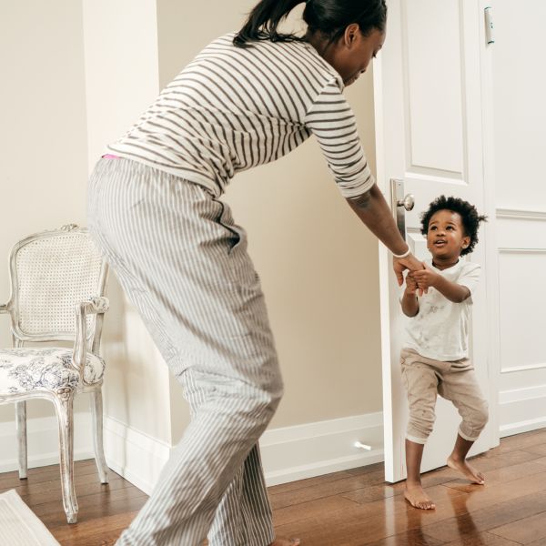Parent and toddler playing joyfully in a cozy room with wooden floors and striped clothing.