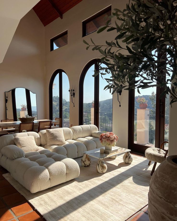 Stylish open-concept living room with arched windows, cozy sofas, and chic decor bathed in natural light.