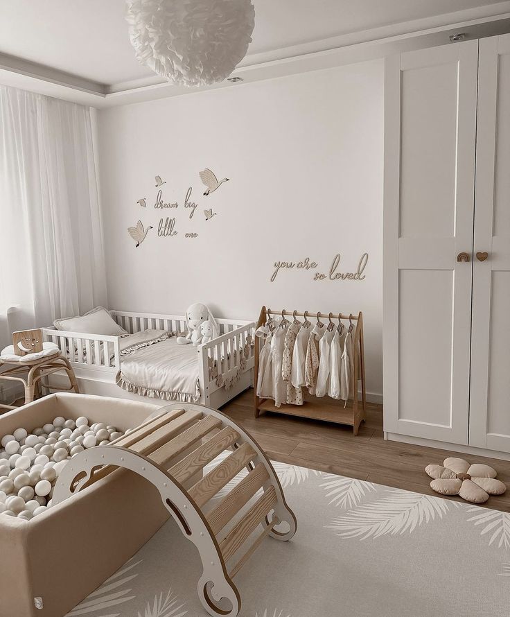Neutral-toned nursery with crib, ball pit, and wooden decor, featuring motivational wall quotes for a cozy atmosphere.