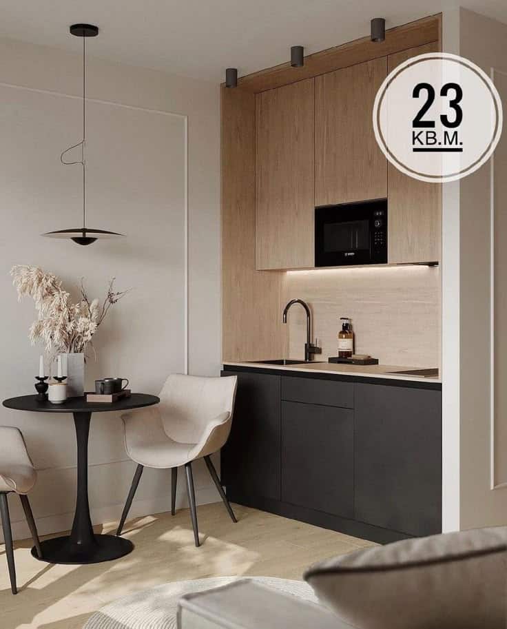 Modern compact kitchen with black and wood cabinets, dining table, and chairs in a stylish 23 sq.m. apartment.