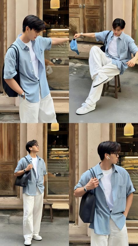 Man in casual blue shirt and white pants poses stylishly outside a rustic building, wearing sunglasses and carrying a bag.
