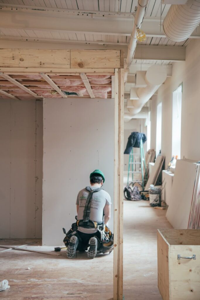 Construction worker installing drywall in a modern building under renovation.