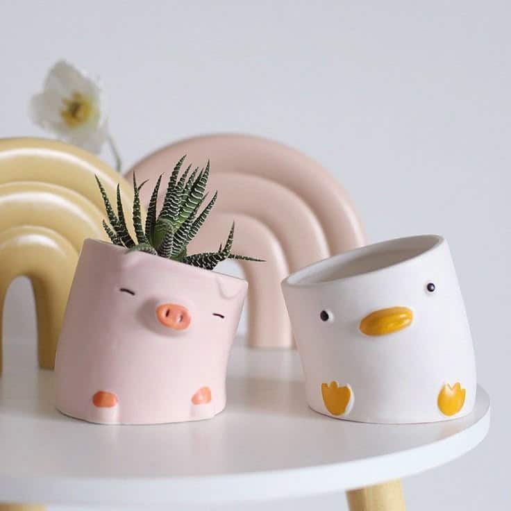 Cute pig and duck ceramic planters on table with succulent, stylish decor.