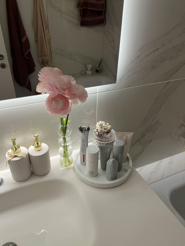 Elegant bathroom vanity with skincare products and pink flowers in a vase, creating a serene and organized space.