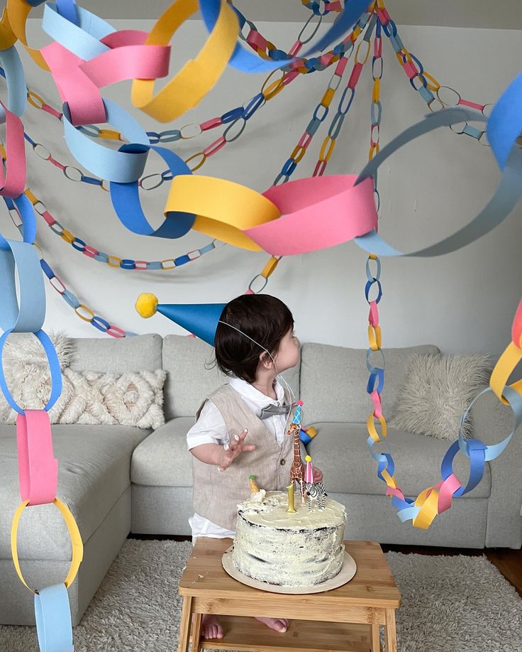 Toddler's birthday party with paper chains, cake, and festive hat.