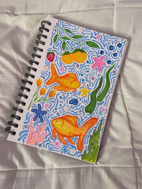 Colorful notebook page with vibrant fish, seaweed, and starfish doodles on a white quilted background.