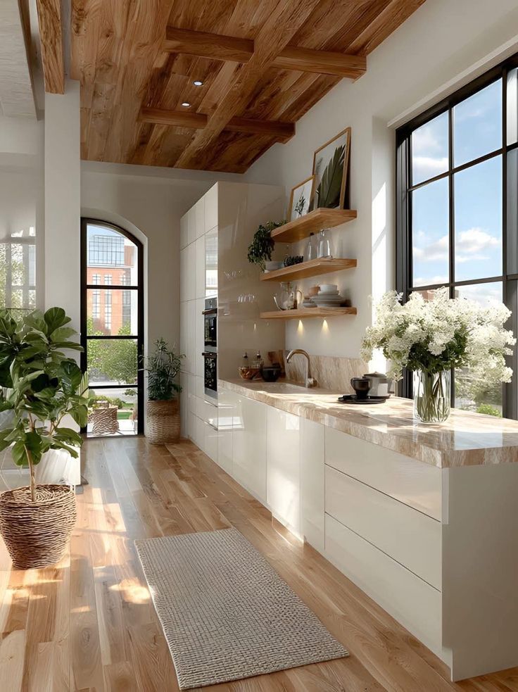 Modern kitchen with wooden ceiling, natural light, white cabinets, open shelves, and potted plants.