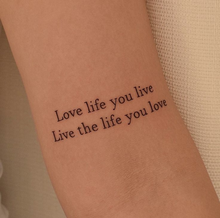 Love life you live tattoo on arm; minimalist text design for inspiration and personal expression.