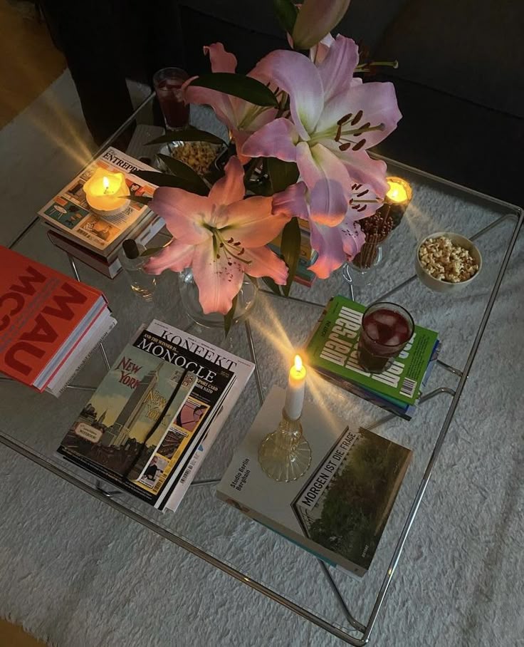 80e0b72c-281f-44b2-9d70-4983089b13ad Cozy coffee table with pink lilies, lit candles, books, and snacks in a stylish living room setting. | Sky Rye Design Cozy coffee table with pink lilies, lit candles, books, and snacks in a stylish living room setting.