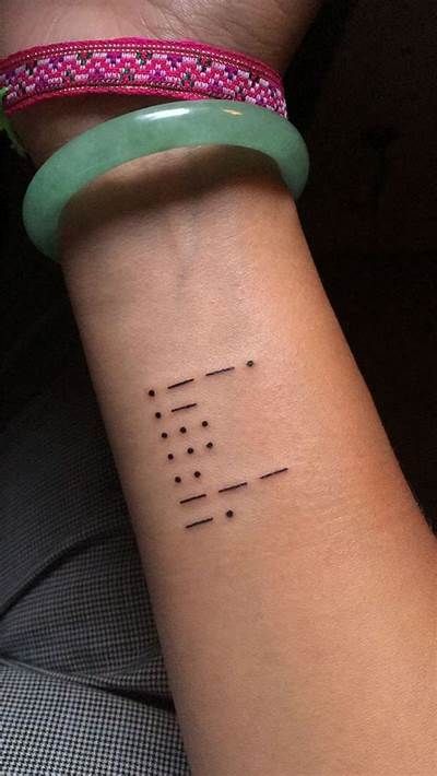 Minimalist Morse code tattoo on forearm, with colorful and jade bracelets for added style.