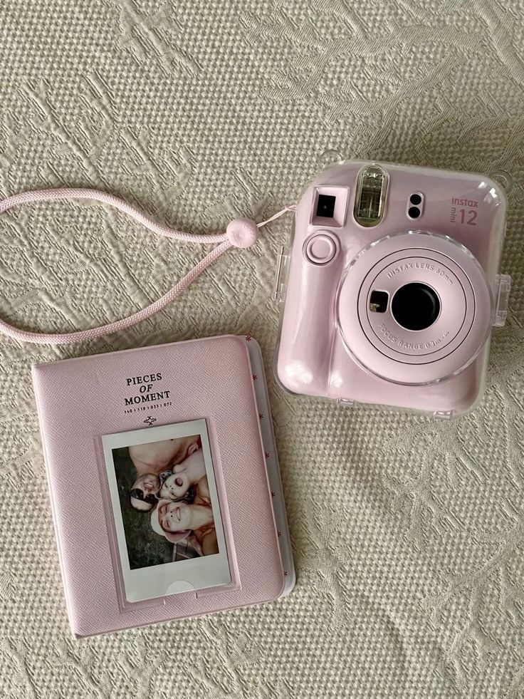 86e92208-cf23-4386-b237-886afb1d5cfe Pink instant camera beside a matching photo album on a textured surface. | Sky Rye Design Pink instant camera beside a matching photo album on a textured surface.