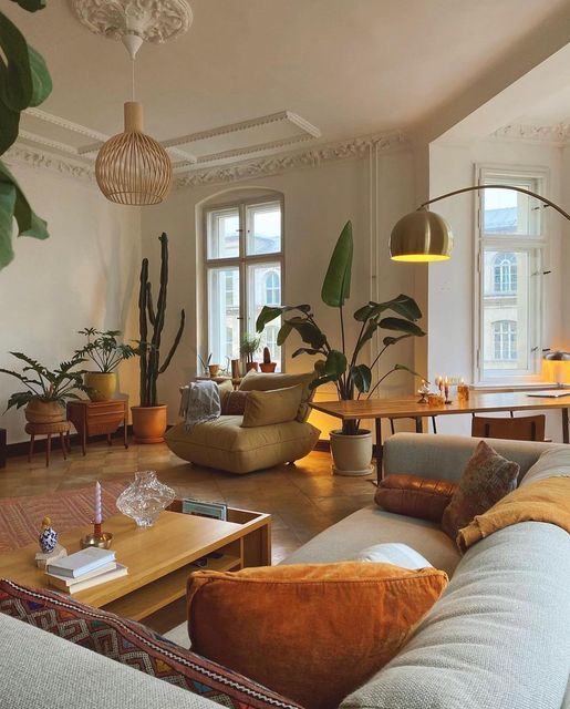 Cozy living room with plants, large windows, modern furniture, and soft lighting for a relaxing ambiance.