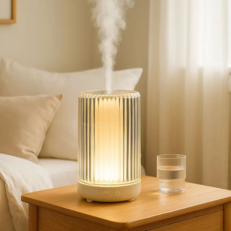 Modern air humidifier with ambient light on bedside table, enhancing cozy bedroom atmosphere.