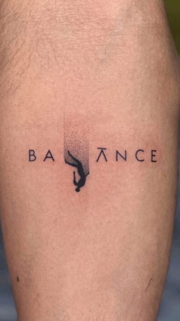 Tattoo of the word BALANCE with a falling figure as the letter L on skin, symbolizing harmony and equilibrium.