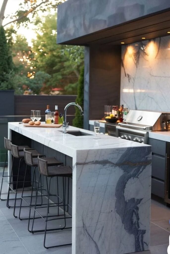 Modern outdoor kitchen with marble countertops, bar stools, grill, and drinks. Elegant and stylish patio setup.