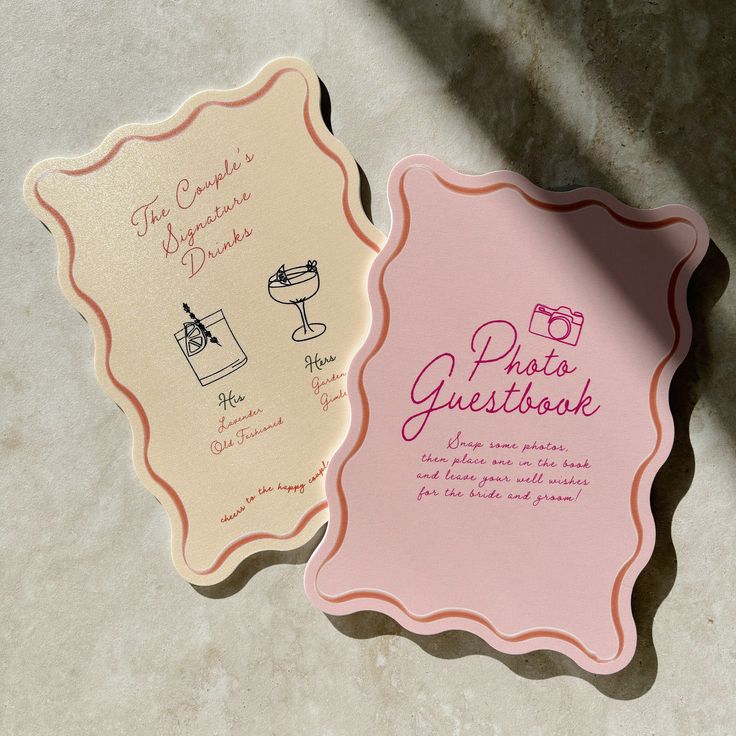Wedding cards with signature drinks and photo guestbook instructions on a textured surface.