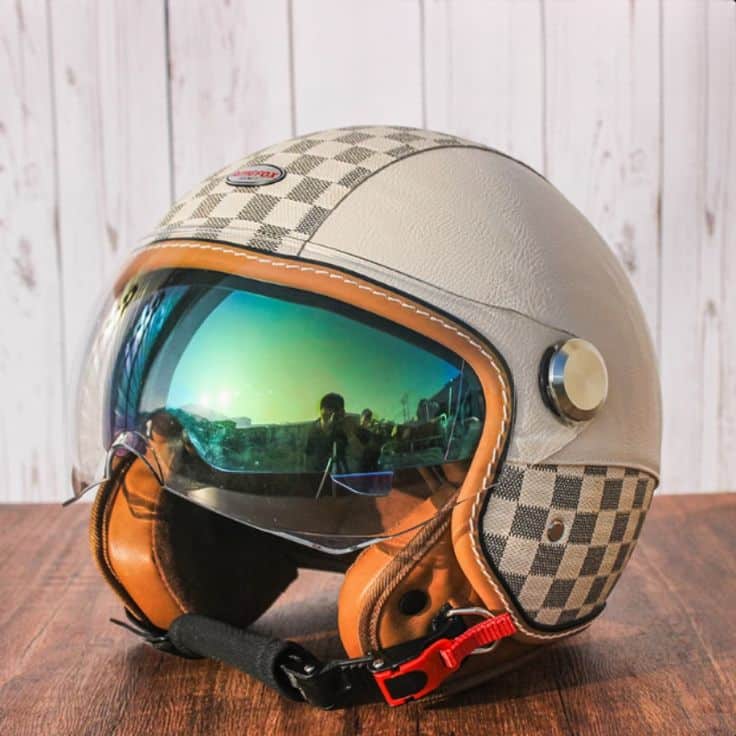 Vintage-style motorcycle helmet with checkered design and reflective visor on wooden surface.