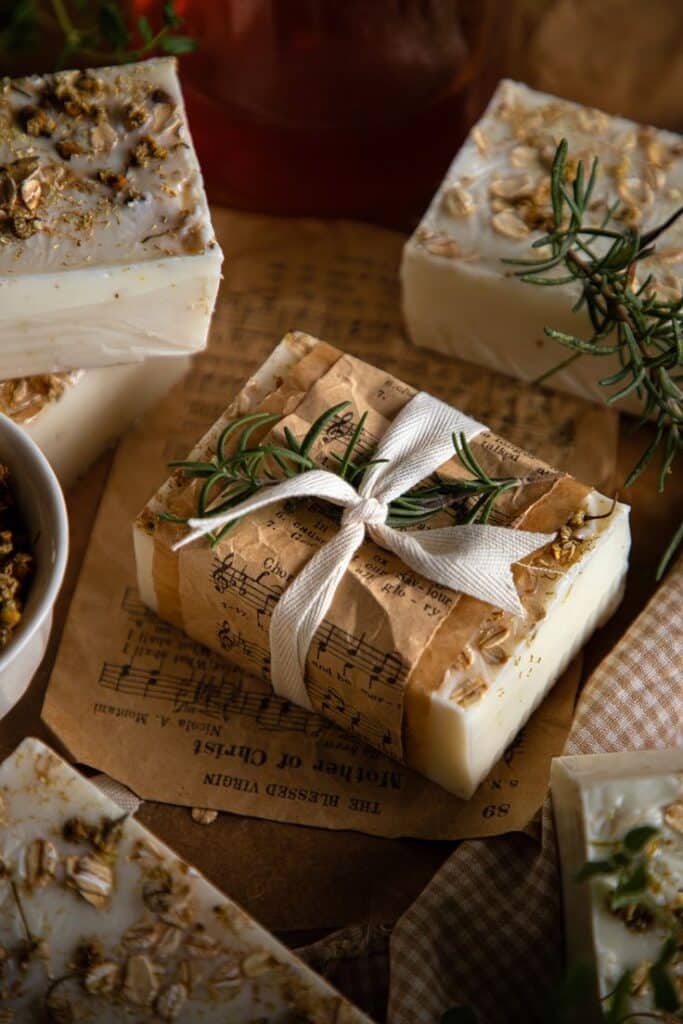 Handmade soap wrapped in vintage paper with rosemary garnish, atop a rustic setting with musical notes.