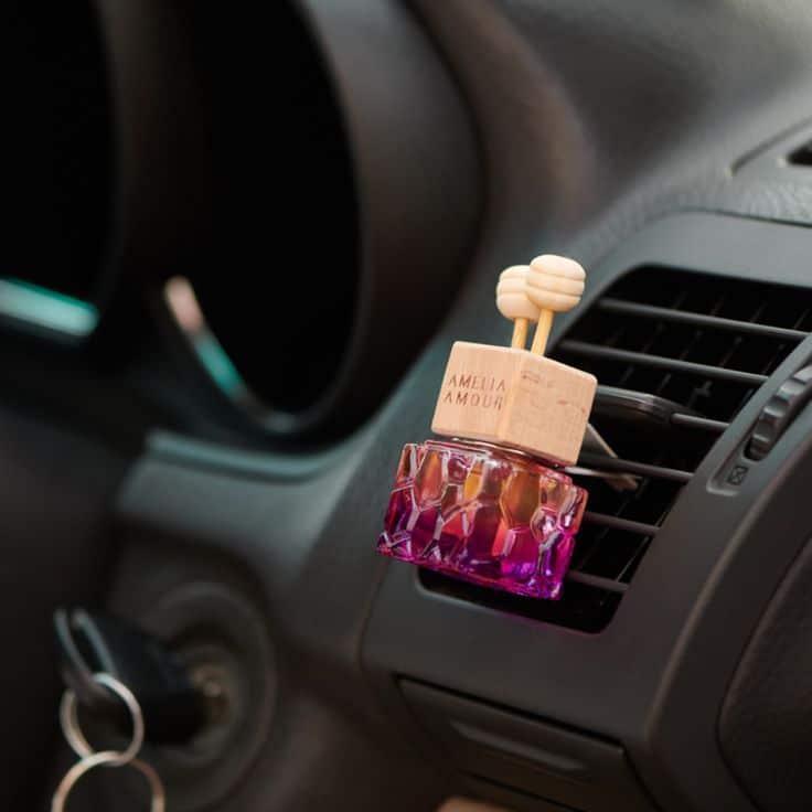 Pink car air freshener attached to a vent, enhancing the vehicle's interior with fragrance and style.