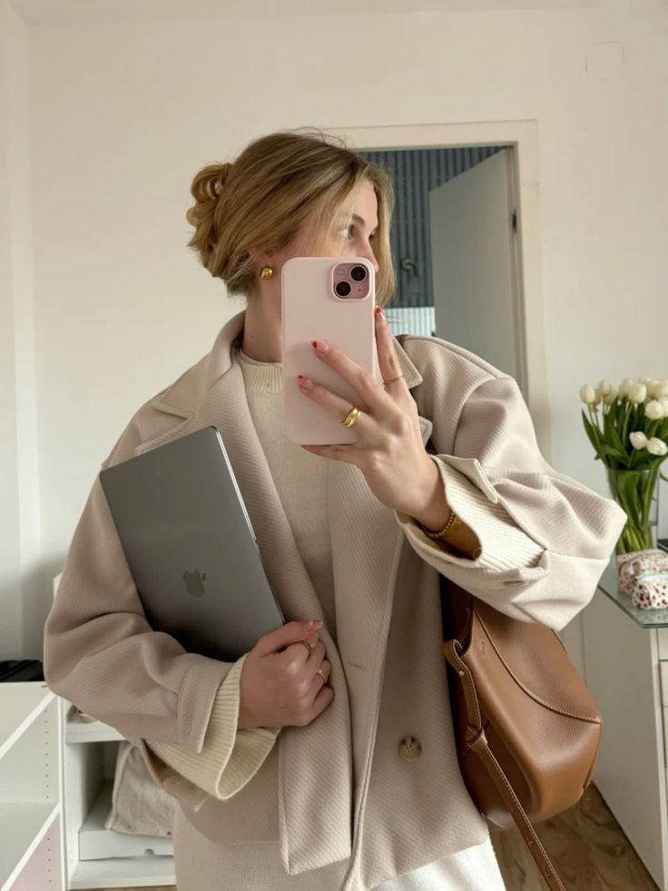 9ce19960-b1ec-4dd7-9bdf-b31da101d2cc Person takes a mirror selfie in a neutral outfit, holding a laptop and wearing a stylish coat. | Sky Rye Design Person takes a mirror selfie in a neutral outfit, holding a laptop and wearing a stylish coat.