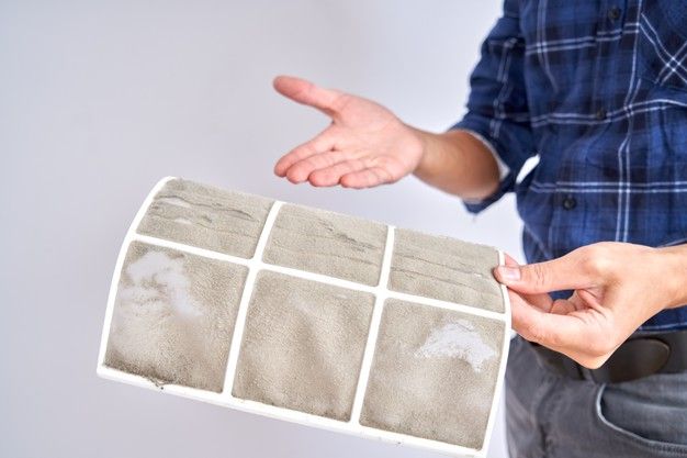 Person showing a dirty air filter, emphasizing the need for regular cleaning to maintain air quality and HVAC efficiency.