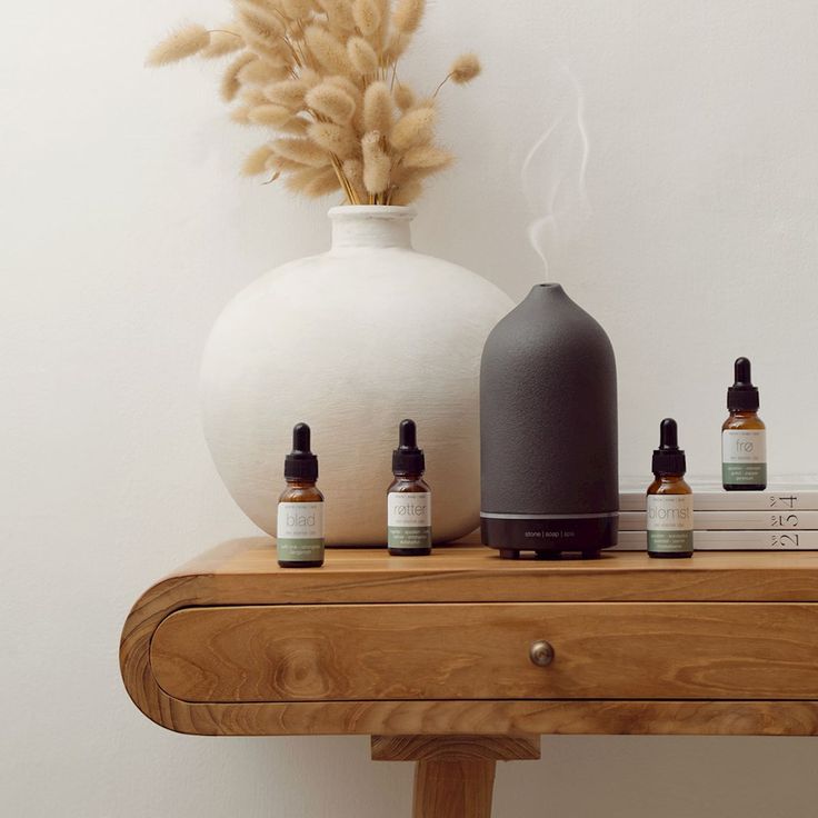 Aromatherapy diffuser on a wooden table with essential oils and decorative vase in minimalist room.