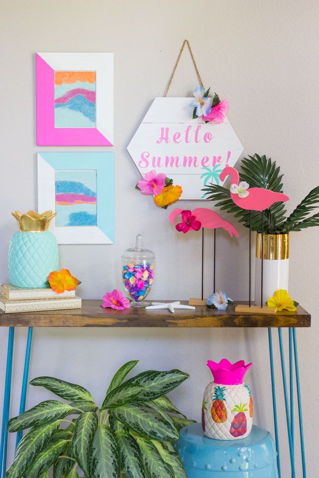 9fc3786a-d2fe-45d4-90a2-2013557386f8 Summer-themed decor with Hello Summer sign, tropical accents, and vibrant plants on a colorful shelf. | Sky Rye Design Summer-themed decor with Hello Summer sign, tropical accents, and vibrant plants on a colorful shelf.