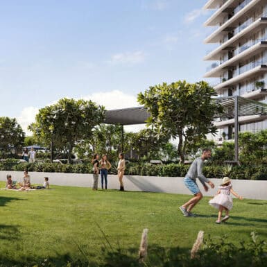 Families enjoying a sunny day in a lush residential garden with modern apartments in the background.