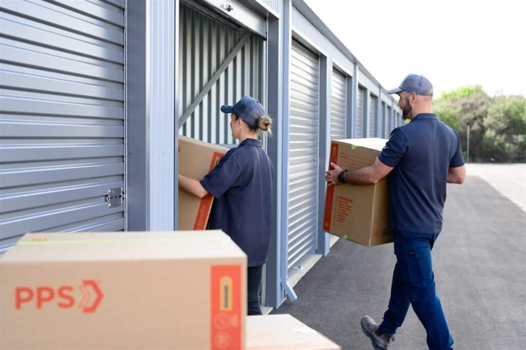 People moving boxes into storage units on a sunny day, showcasing self-storage solutions.