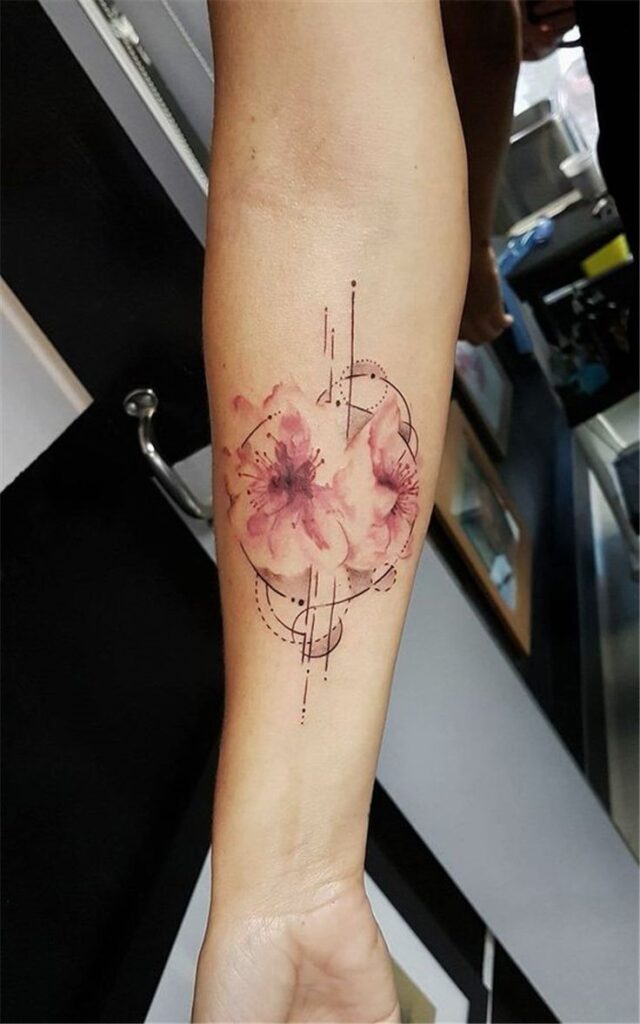 Geometric and watercolor flower tattoo on forearm with artistic dotted lines and circles.