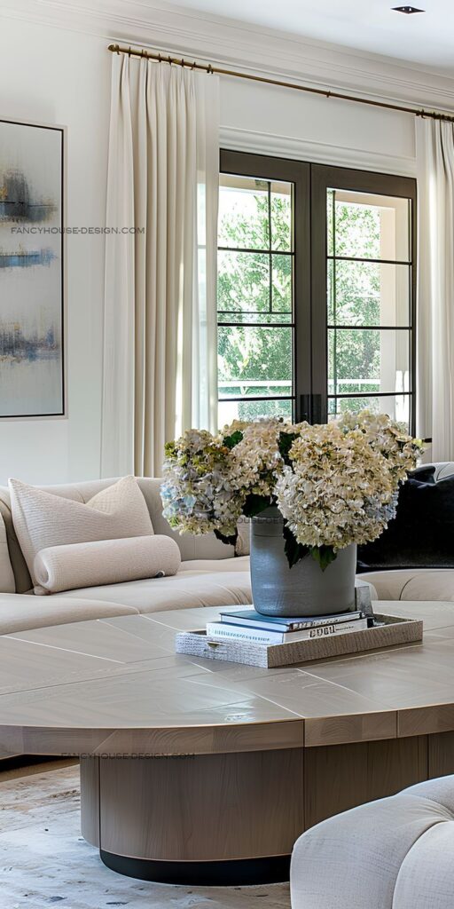 An abundance of natural light floods the living space accentuating its contemporary design Luxurious living room with plush sofa, wooden coffee table, and flowers near large window. | Sky Rye Design Luxurious living room with plush sofa, wooden coffee table, and flowers near large window.