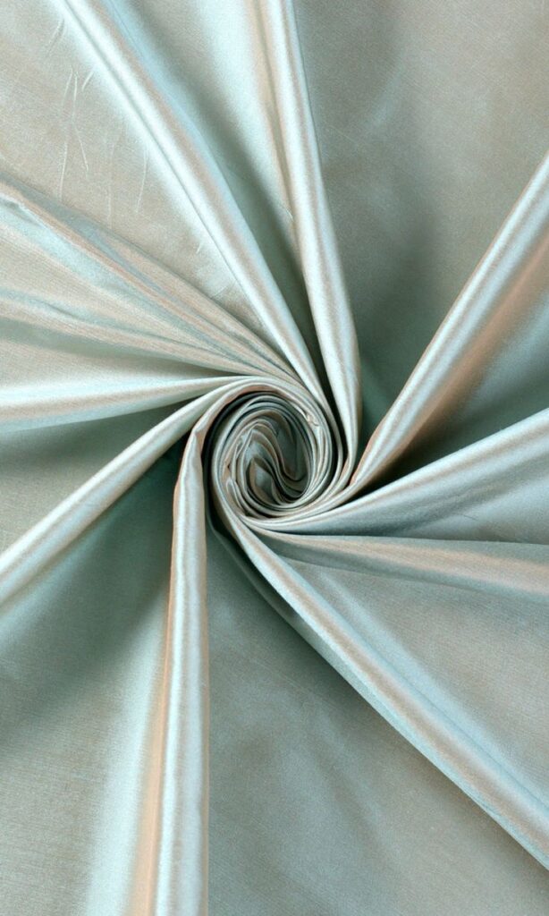Swirling silver satin fabric creating an elegant, soft texture with radiating folds.