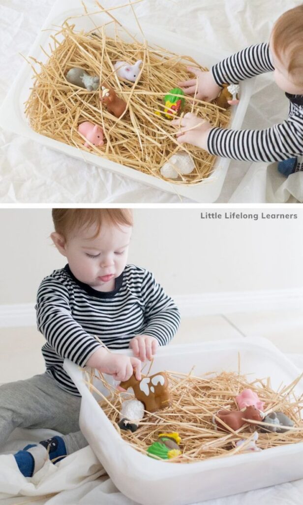 Toddler playing with toy animals in a sensory bin filled with straw, promoting imaginative play and learning.